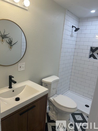 A bathroom with a sink, toilet, and a mirror.