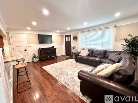 A living room with a brown leather couch and a white rug.