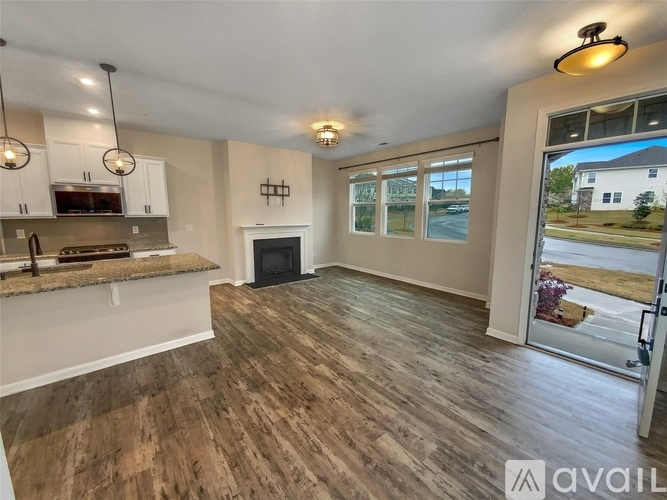 A spacious living room with wood flooring and a kitchen area with stainless steel appliances.