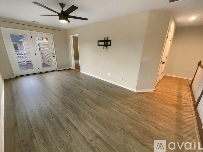A spacious room with wooden flooring and a ceiling fan.