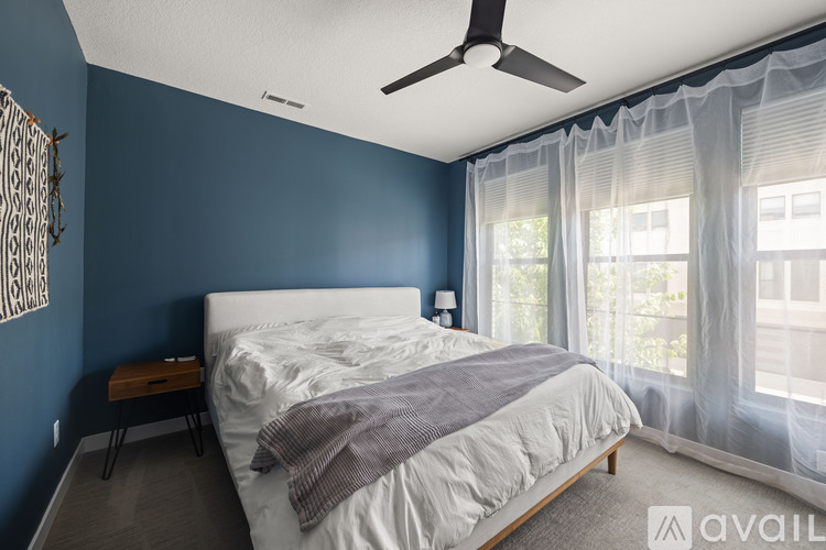 A bedroom with a bed, a ceiling fan, and a window with curtains.