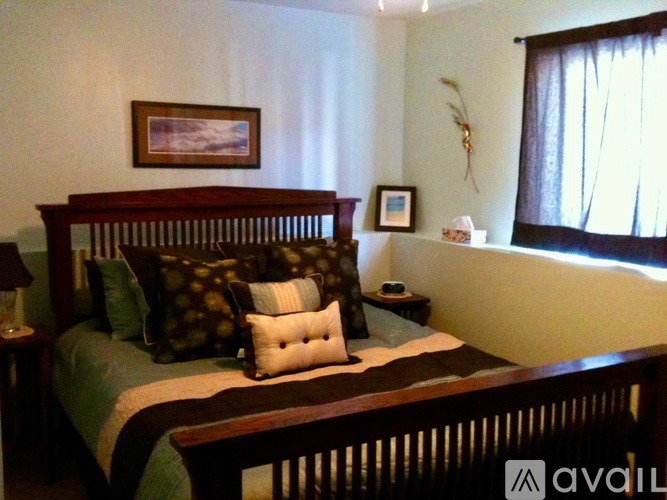 A bedroom with a bed, nightstand, and a painting on the wall.