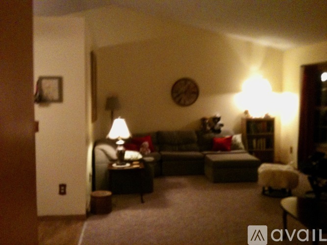 A living room with a couch, a lamp, and a clock on the wall.