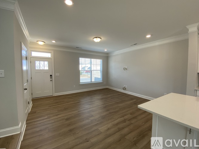 A spacious room with wooden flooring and white walls.