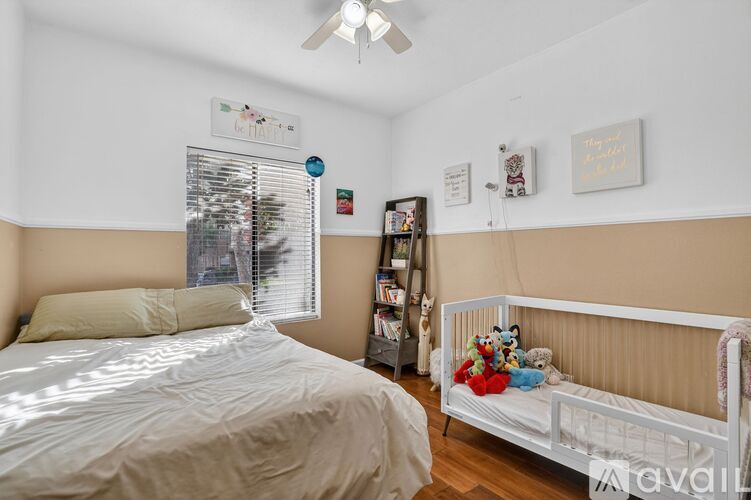 A bedroom with a white bed and a window with blinds.
