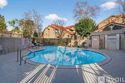 A pool surrounded by a concrete patio and a fence.