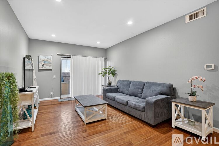 A living room with a grey couch and wooden floors.