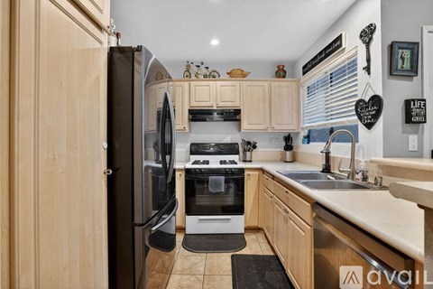 A kitchen with wooden cabinets and a black refrigerator.