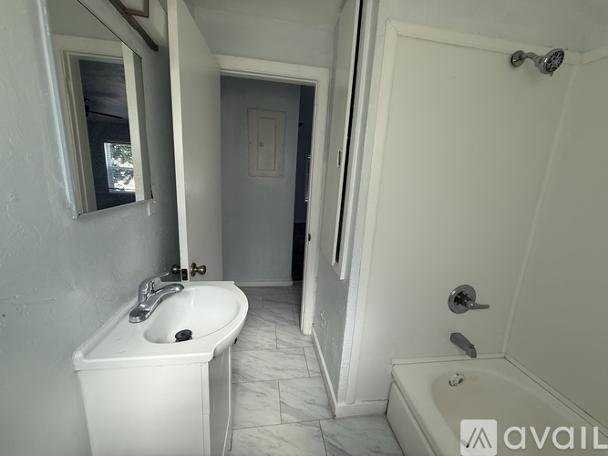 A white bathroom with a sink, mirror, and bathtub.