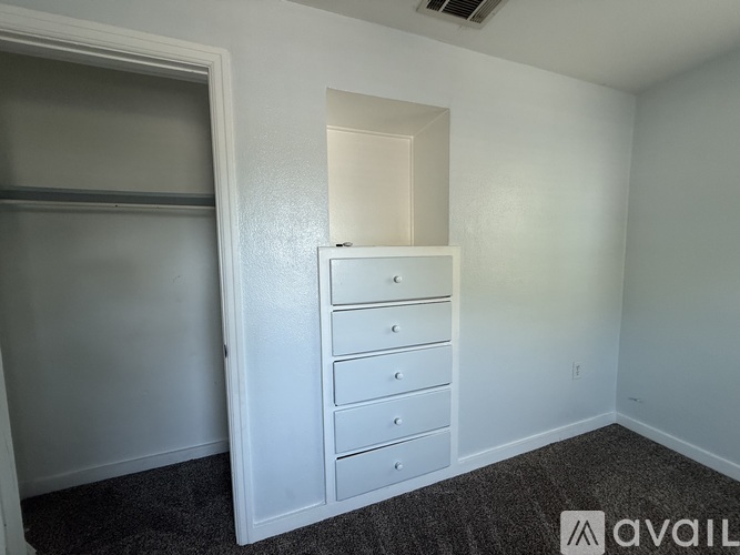 A room with a white dresser and a grey carpet.