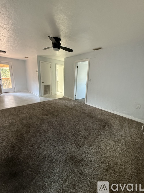 A room with a ceiling fan and carpeted floor.