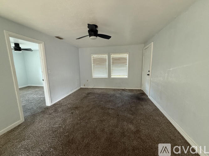 A room with a carpeted floor and a ceiling fan.