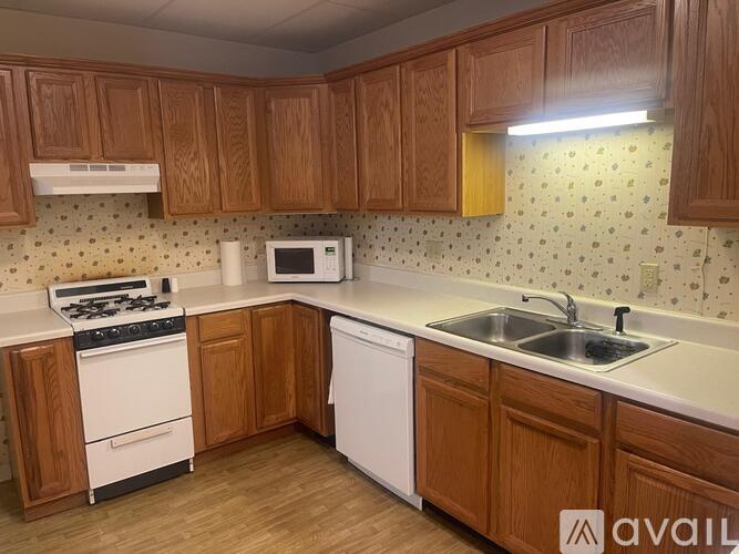 A kitchen with wooden cabinets and a white dishwasher.