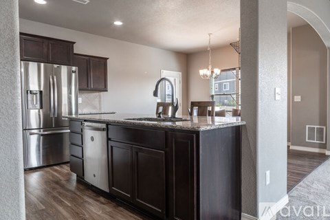 A kitchen with dark wood cabinets and a granite countertop.