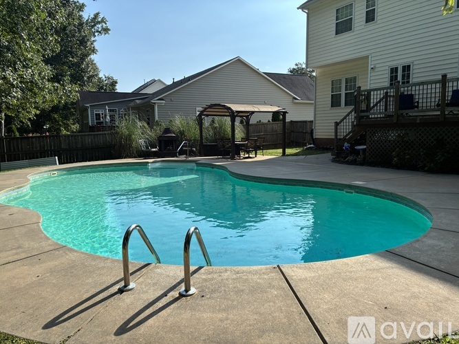 A small residential pool with a concrete deck and a metal fence.