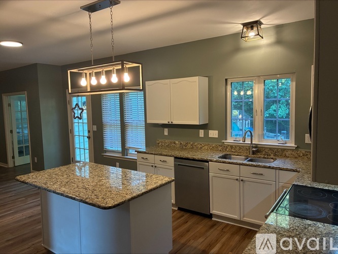 A kitchen with a granite countertop and a window with blinds.