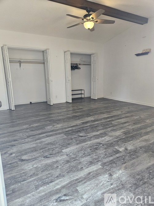 A room with a ceiling fan and a grey floor.