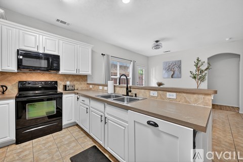 A kitchen with white cabinets and a black oven.