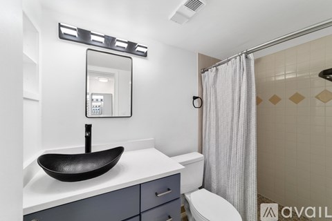 A bathroom with a black sink and a shower with a curtain.