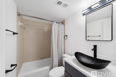 A bathroom with a black sink and a white tub.