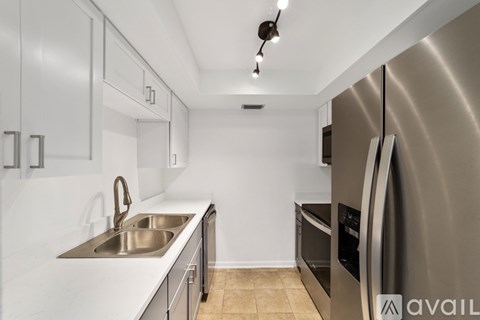 A modern kitchen with a stainless steel refrigerator and a double sink.