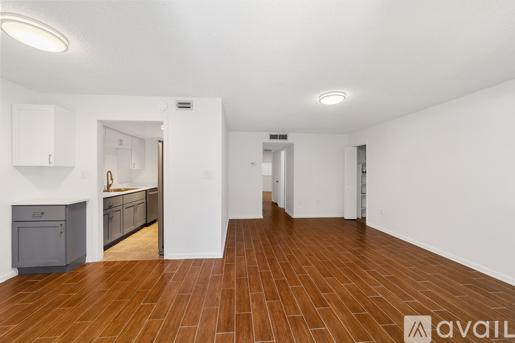 A spacious room with wooden flooring and white walls.