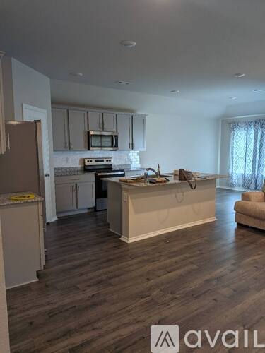A kitchen with a refrigerator, microwave, oven, and sink.
