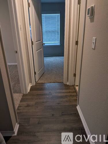 A hallway with wood flooring and white walls.