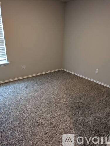 A room with a carpeted floor and a window with blinds.