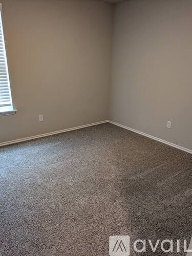 A room with a carpeted floor and a window with blinds.