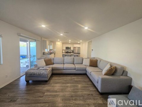 A spacious living room with a grey sofa and a grey ottoman.