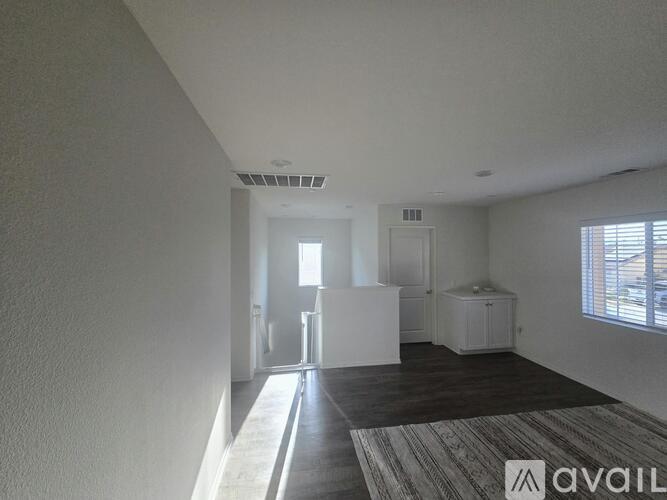 A spacious room with a rug on the floor and a cabinet in the corner.