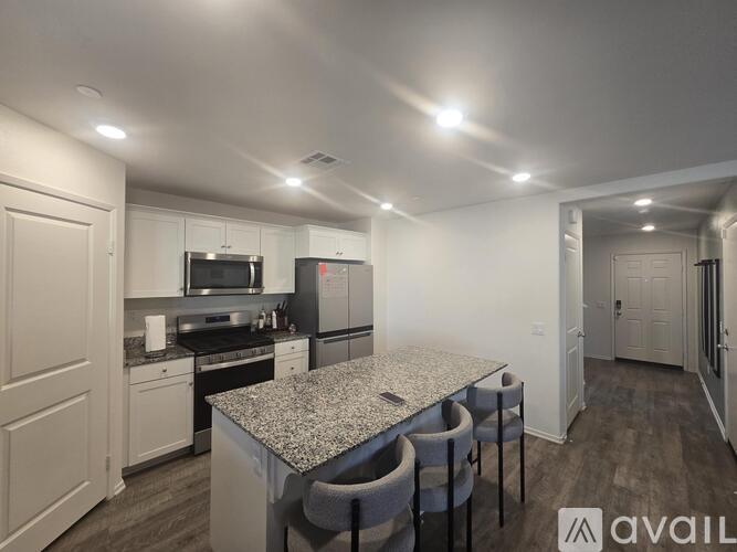 A kitchen with granite countertops and a dining table with chairs.