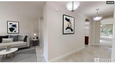 A living room with a white couch and two framed pictures on the wall.