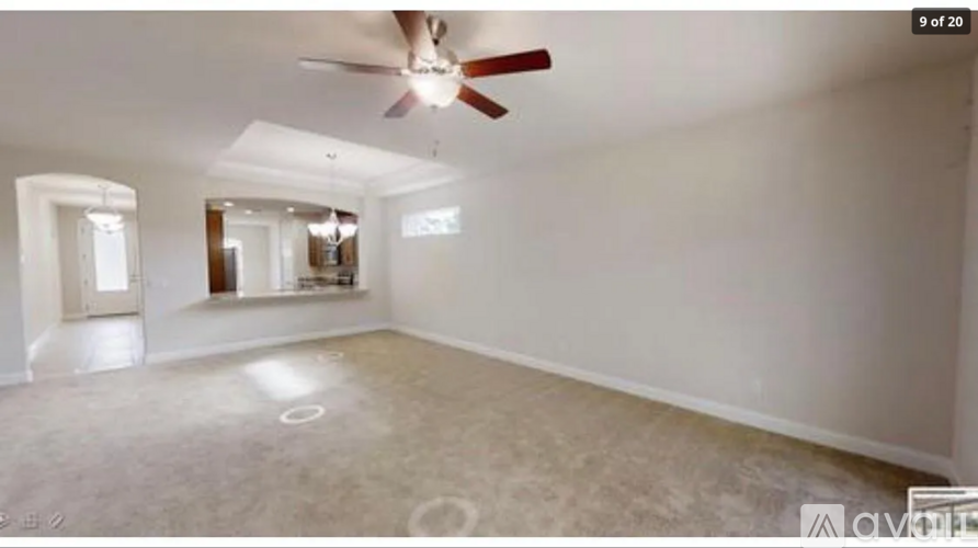 A spacious room with a ceiling fan and a large mirror on the wall.