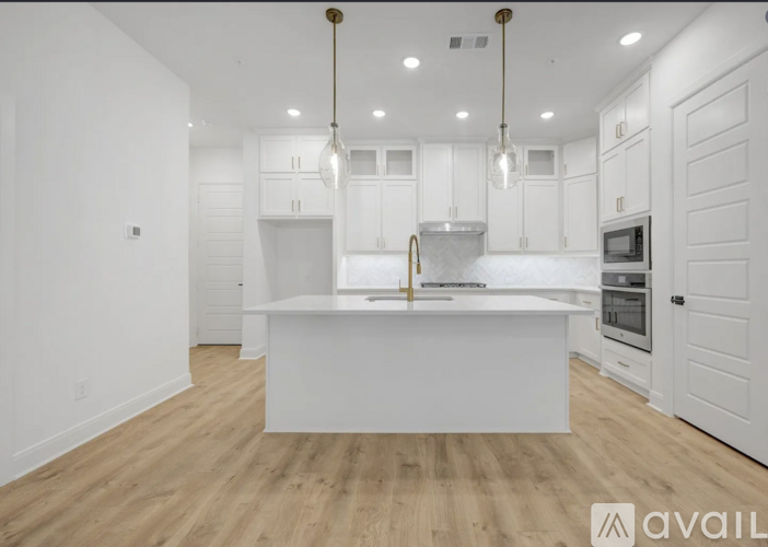 A modern kitchen with white cabinets and a wooden floor.