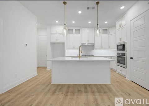 A modern kitchen with white cabinets and a wooden floor.
