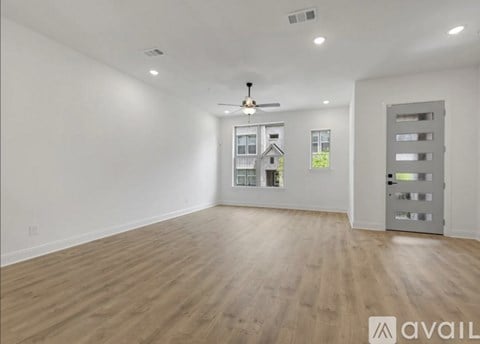 A spacious room with wooden flooring and a ceiling fan.