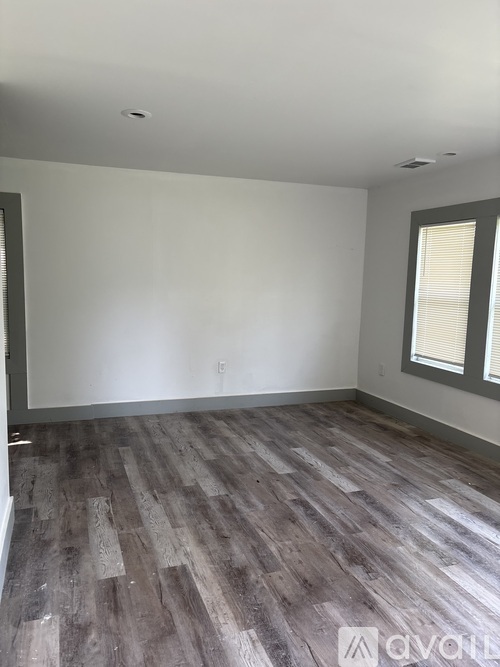 A room with wooden flooring and a window with blinds.