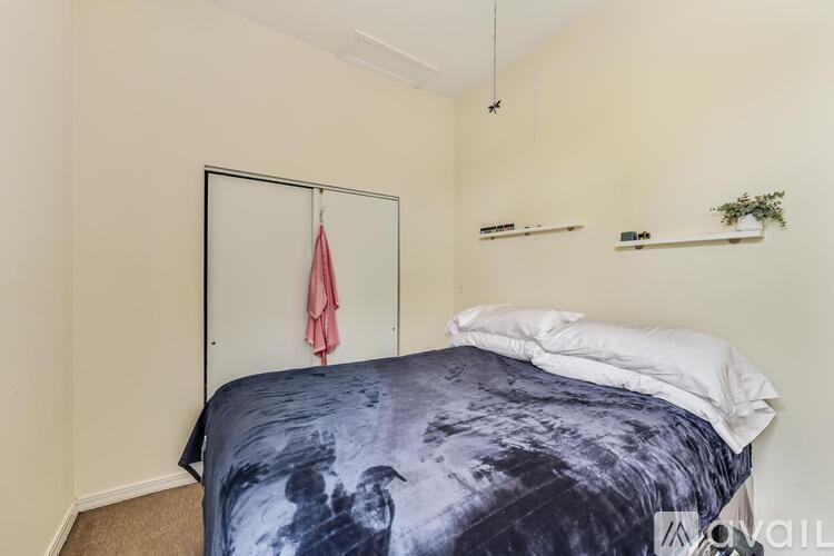 A bedroom with a bed and a red towel hanging on a door.