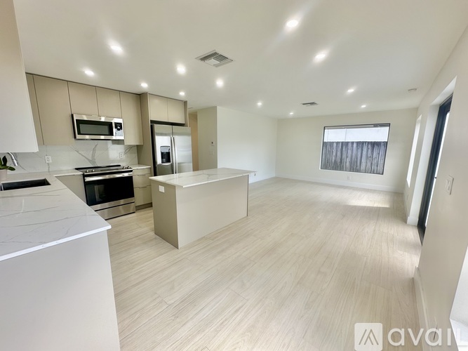 A modern kitchen with a white countertop and stainless steel appliances.