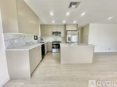 A modern kitchen with white cabinets and a marble countertop.