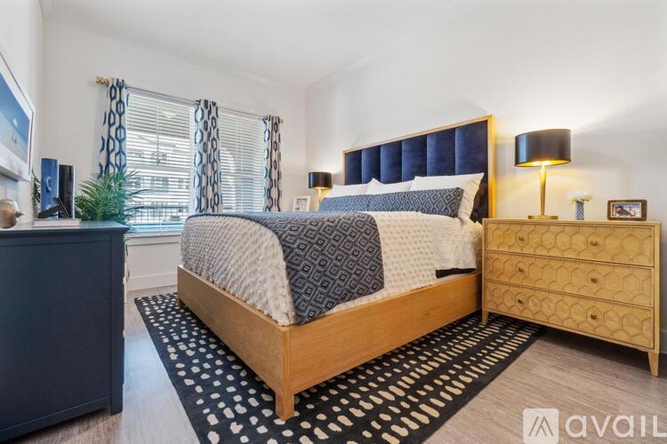 A bedroom with a bed, nightstand, and window with curtains.