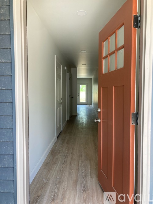 A hallway with a brown door and white walls.