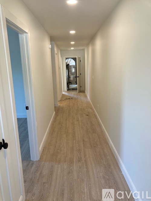 A long hallway with wood flooring and white walls.
