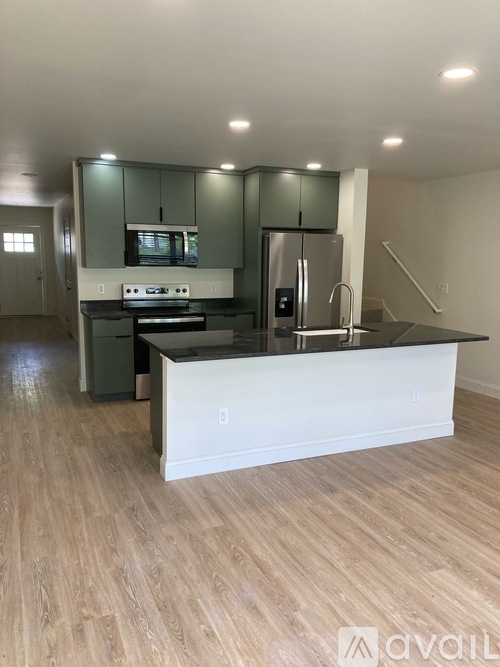 A kitchen with a white island and wooden floors.