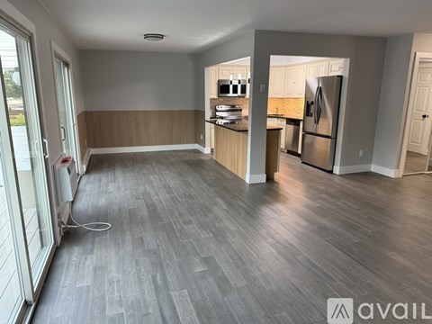 A kitchen with a refrigerator, sink, and cabinets is visible through a doorway.