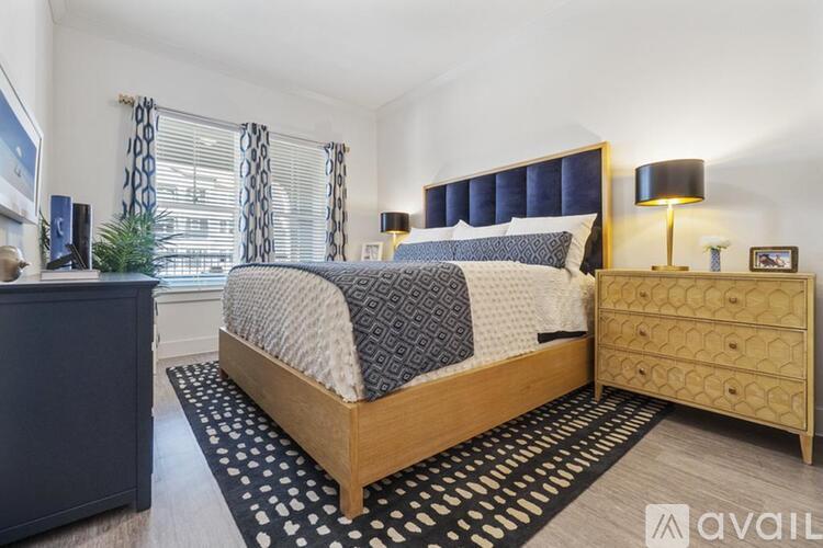A bedroom with a bed, nightstand, and a plant.