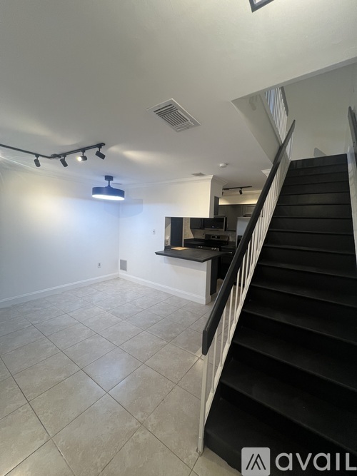 A spacious room with a staircase leading to the upper level.