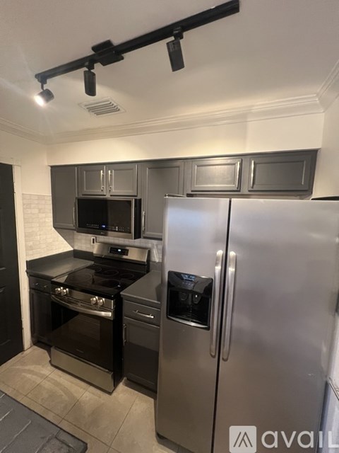 A modern kitchen with a stainless steel refrigerator and black appliances.